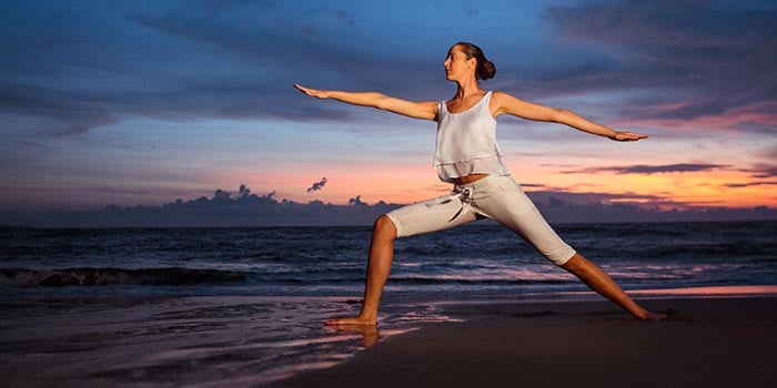 Frau macht Yoga am Strand, um sich zu entspannen