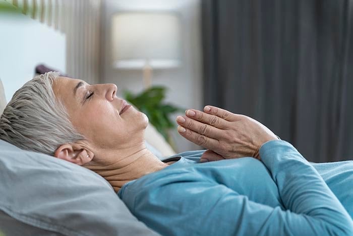 žena praktikující řízenou meditaci pro spánek ležící v posteli