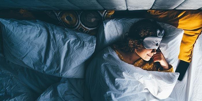 femme dormant avec un masque de sommeil sur les yeux importance de l'hygiène des habitudes saines