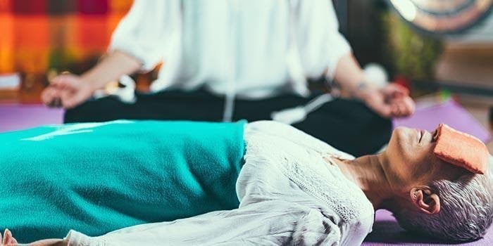 ældre kvinde laver søvnmeditation på gulvet