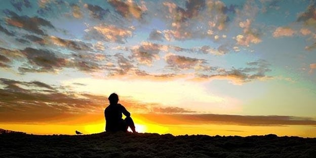 kvinna som sitter och njuter av soluppgången och inleder dagen med en morgonmeditation