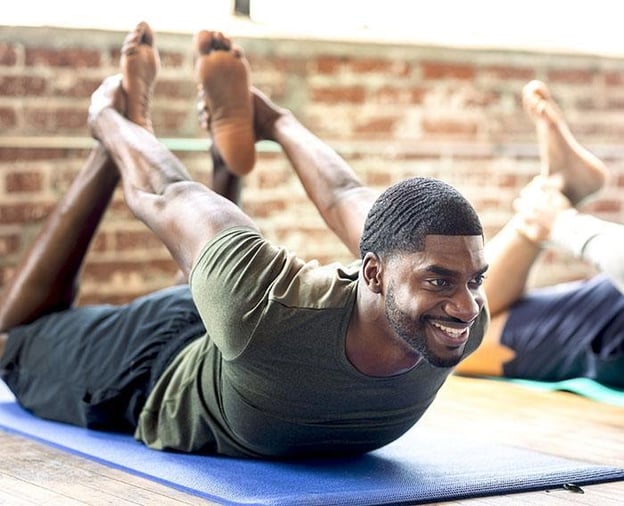 man som prövar yoga för män i en yogaklass