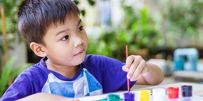 boy painting and coloring in the classroom