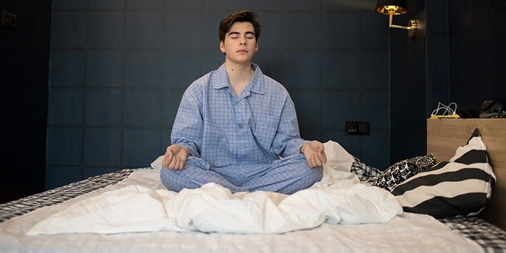 muž praktikující spánkovou meditaci, aby zlepšil kvalitu svého spánku.