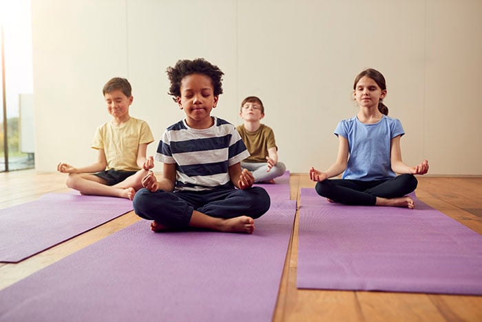 group-of-children-sitting-on-exercise-mats-and-meditating-700