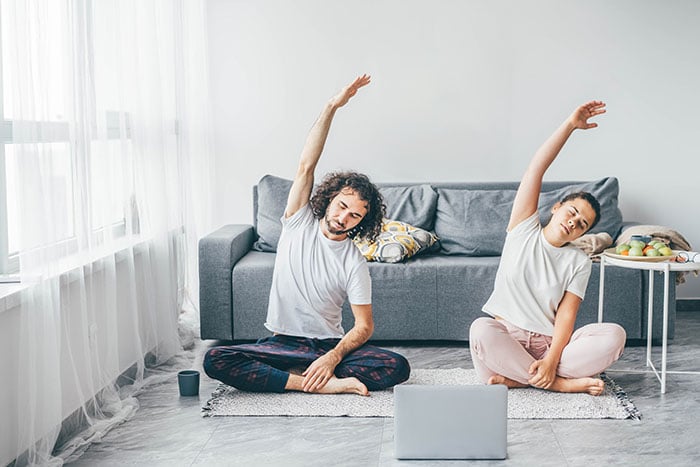 man and woman in pajamas practice gentle yoga sitting on the floor