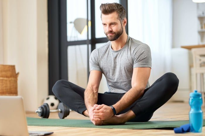young man using laptop and working out at home
