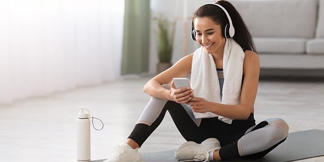 woman sitting on a yoga mat listening to music