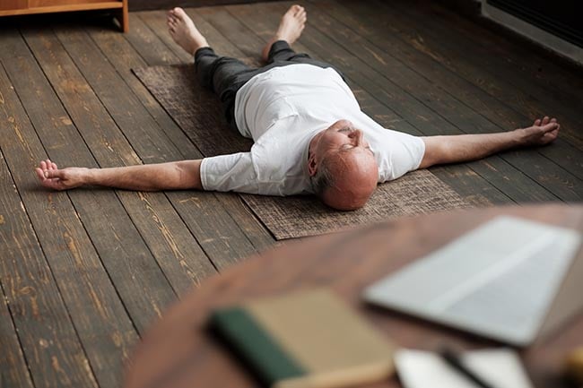 мужчина медитирует на деревянном полу, ощущая преимущества йога-нидры