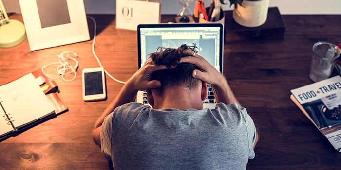 en man framför en dator som känner sig för stressad