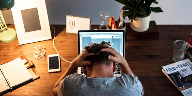 stressed man sitting in front of a laptop