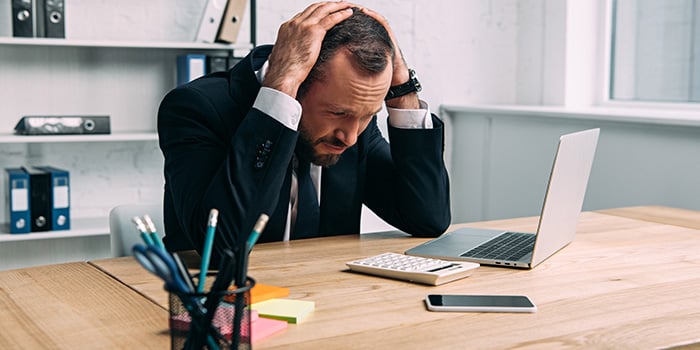 en affärsman som sitter framför sin dator och känner sig stressad