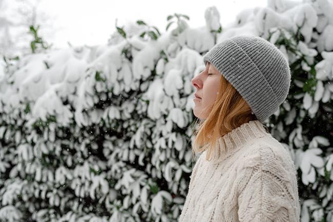 young woman breathes fresh frosty air outdoors