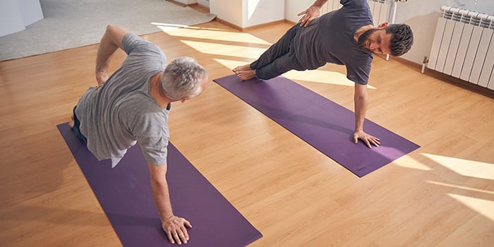 dos hombres haciendo yoga en casa