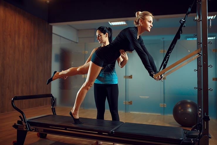 femme faisant de l'exercice avec un instructeur de pilates