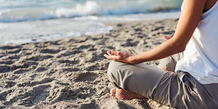 vrouw die de meditatie van de lichaamsaftasten op het strand doet