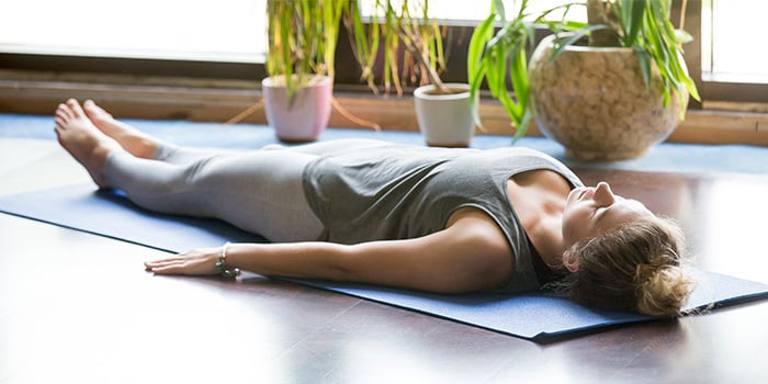 woman-doing-yoga-at-home-shavasana-pose-as-part-of-yoga-nidra-700