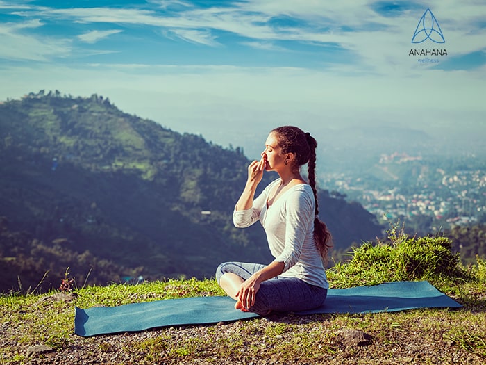 woman practices alternate nostril breathing in lotus pose outdoors