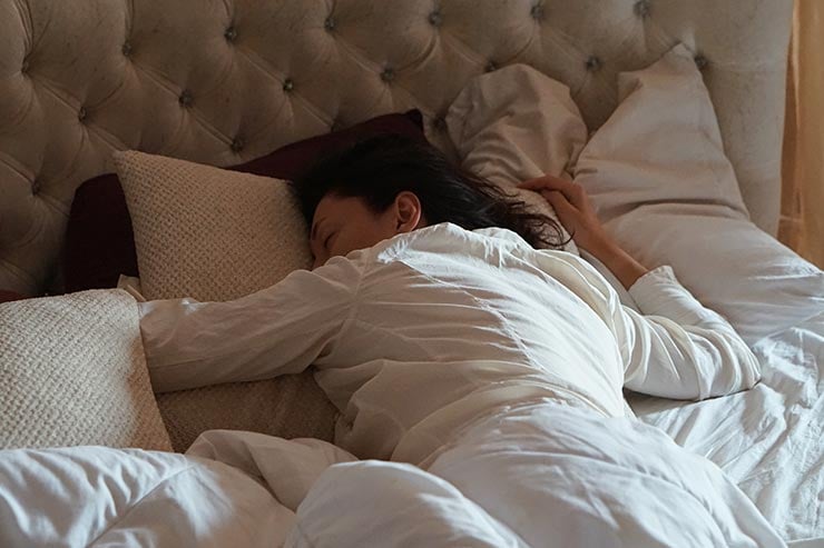 femeie dormind pe burtă în pat
