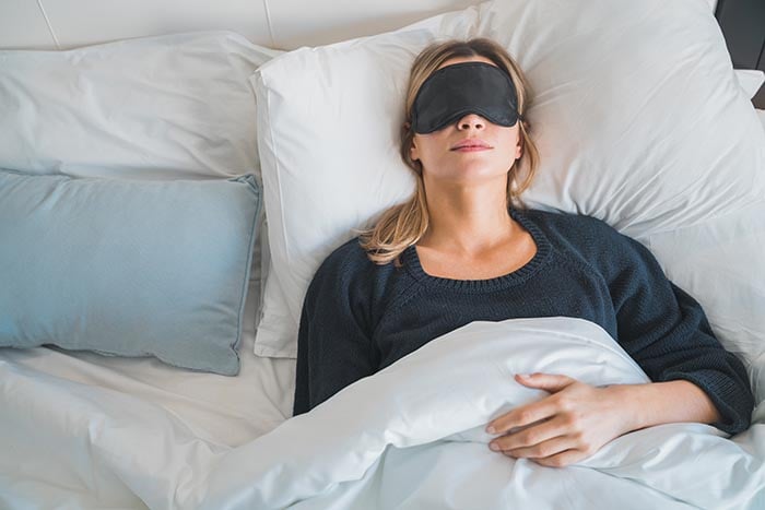 kvinna som sover med ögonmask för att hålla ljuset ute