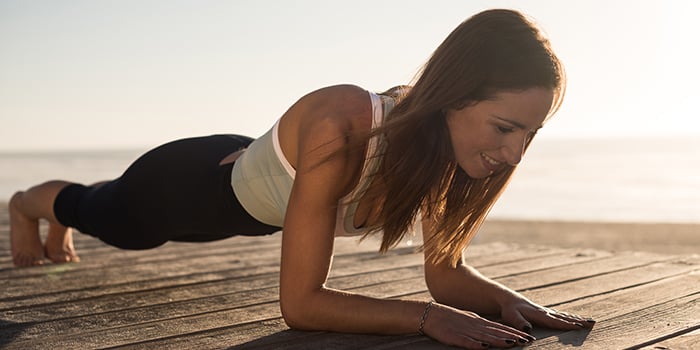 kvinna som utövar pilates och yoga på stranden