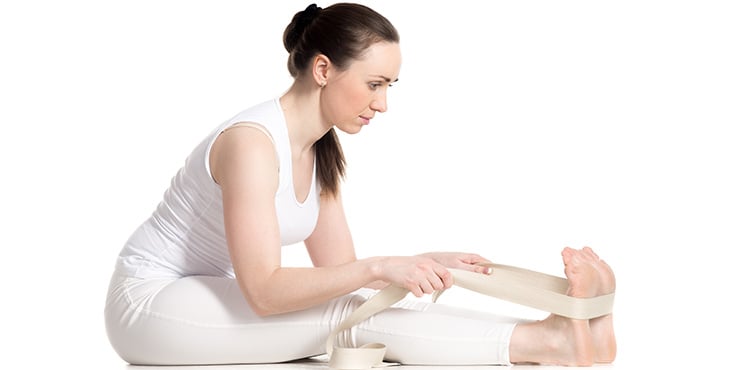 woman doing yoga with props in seated forward bend pose