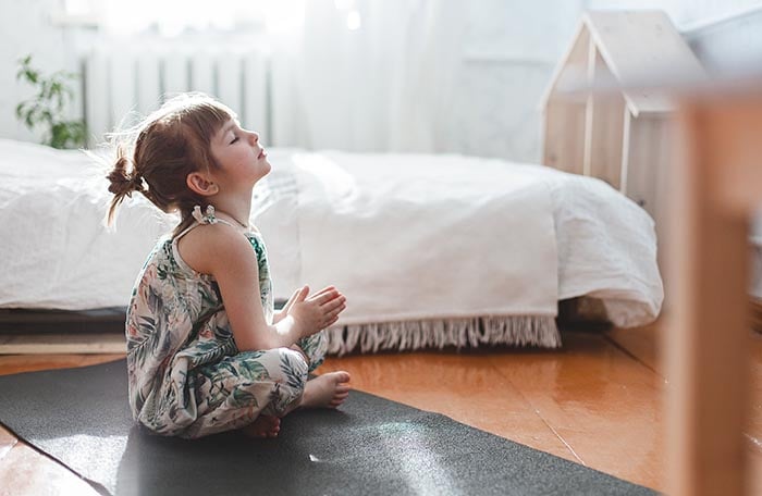 ung flicka som sitter på golvet och tränar olika andingsövningar
