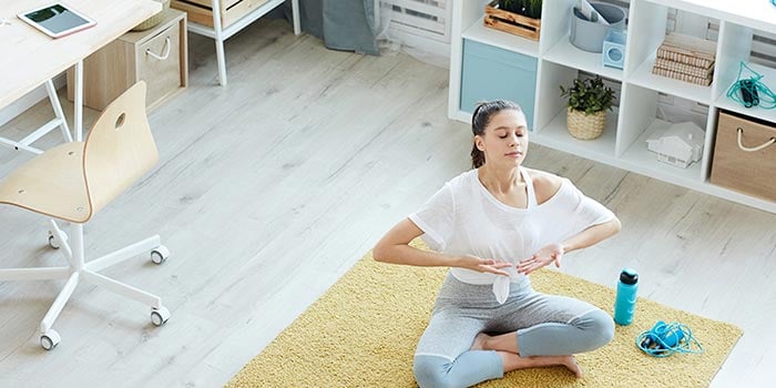 Unga kvinna som utför meditationsövningar för andning i hemmet och gör 4 7 8 andning