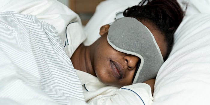 Woman sleeping using a eye mask, to not have her sleep disturbed by the light