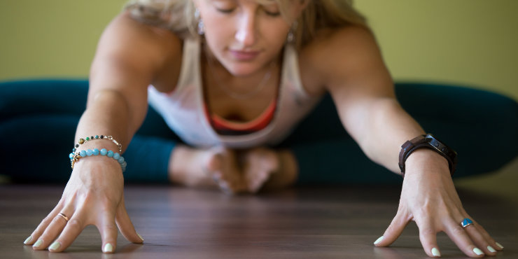 Kvinna som böjer sig framåt i fjäril yin yogaställning