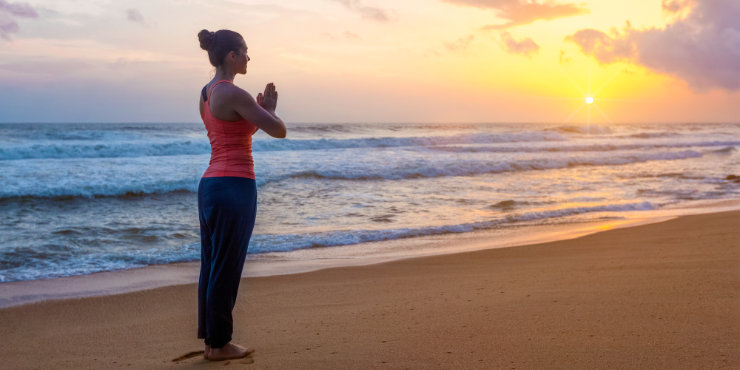 kobieta wykonująca pozę górską (tadasana) na plaży