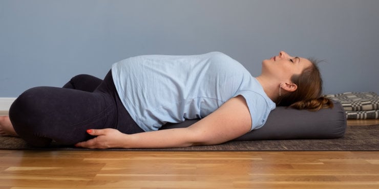 restorative yoga zwangere vrouw ondersteund.