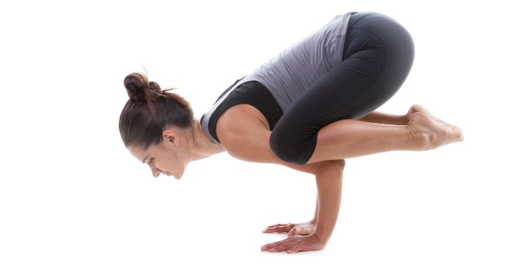 mujer haciendo la postura del cuervo bakasana