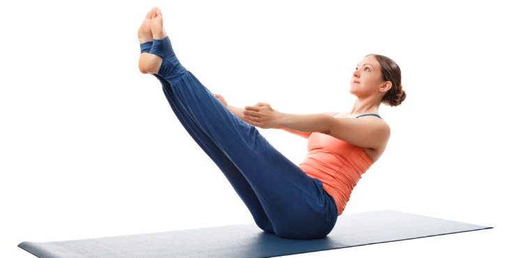 Une femme pratique la pose du bateau Paripurna Navasana en yoga.