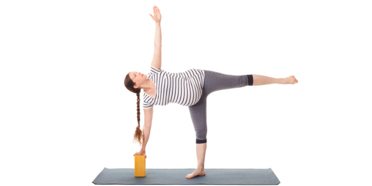 femme debout dans la pose de la demi-lune en utilisant un bloc