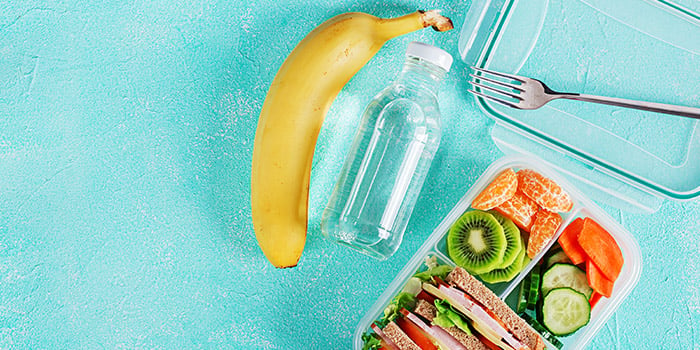 Boîte à lunch scolaire aux habitudes saines avec un sandwich, des légumes, de l’eau et une banane