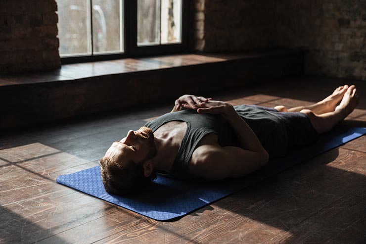 Mann übt die Body Scan Meditation in einem Haus