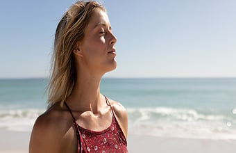 Jovem mulher caucasiana respirando enquanto caminha na praia, sem se importar com a respiração paradoxal