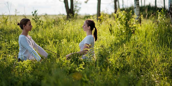 Retrato de duas mulheres jovens curtindo a prática de respiração de ioga Pranayama, respirando ao ar livre