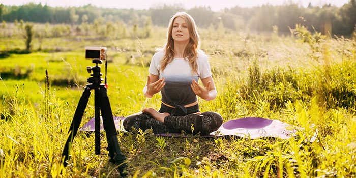 Une fille pratique le yoga dans la nature et enregistre une leçon vidéo de yoga.