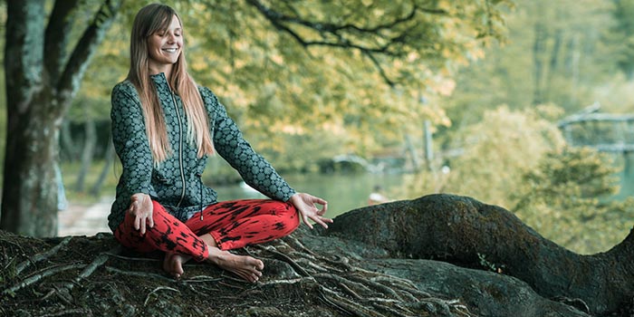  Mujer haciendo meditación consciente al aire libre para ayudarla a lidiar con el estrés y la presión