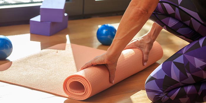 woman rolling up a yoga mat after yoga class