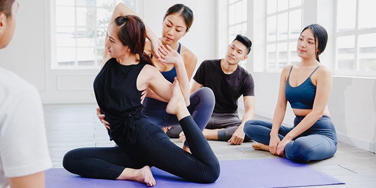 mulher ensinando yoga a um grupo de estudantes