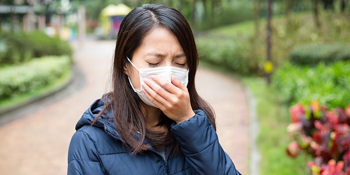 woman wearing a facemask suffering from breathing problems, such as dyspnea