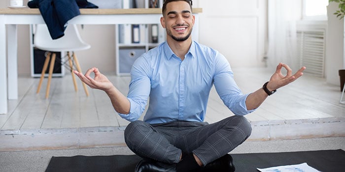hombre sentado en el suelo realizando actividades de manejo del estrés para reducir el estrés en su vida diaria