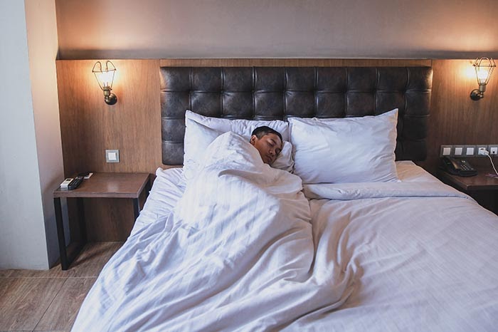 man getting the sleep he needs on his bed