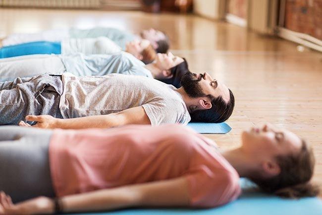 en grupp som övar yoga nidra för att dra nytta av fördelarna som denna yoga medför