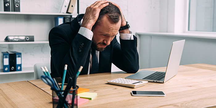 en affärsman som sitter framför sin dator och känner sig stressad