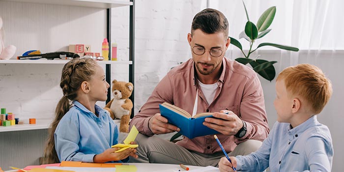 teacher reading a book to children around a table