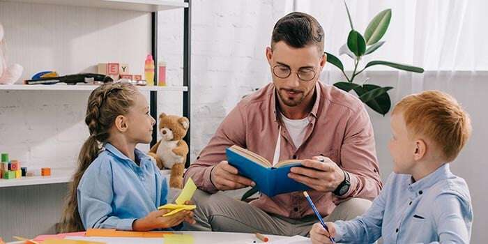 teacher reading a book to children around a table
